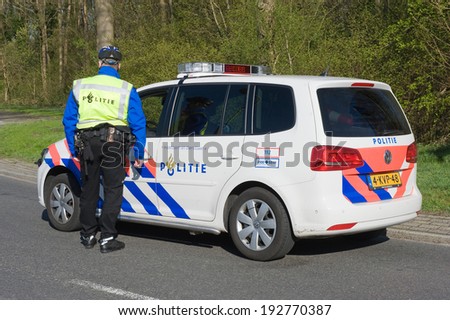 ENSCHEDE, NETHERLANDS - MARCH 25: A policeman is talking to a colleague in a police car during a surveillance on a street, march 25, 2014 in the Netherlands