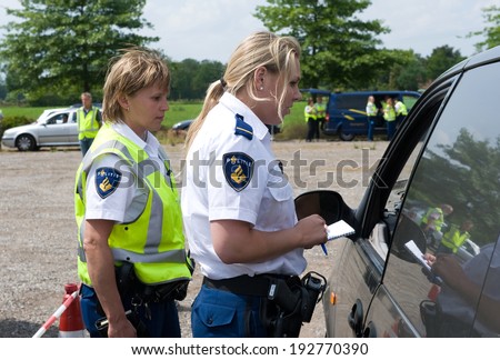 HAAKSBERGEN, NETHERLANDS - JUNE 09: Two policewomen are checking the papers of a car driver during a massive car control, june 09, 2011 in the Netherlands