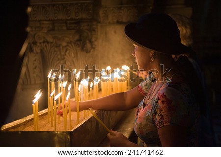 JERUSALEM, ISRAEL - OCT 06, 2014: A woman is burning a candle close at the place where Jesus Christ was crucified in the Church of the Holy Sepulchre in Jerusalem.