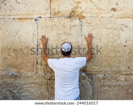 A jewish man is praying against the western wall in the old city of Jerusalem