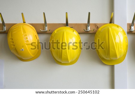 Two helmets hanging on coat hangers on a construction place