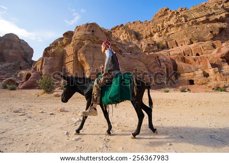 PETRA, JORDAN - 12OCTOBER, 2014: A man is riding on the back of a donkey in Petra in Jordan