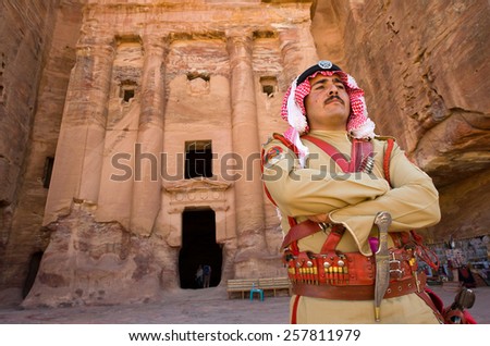 PETRA,  JORDAN - OCT 12, 2014: A guard in ancient costume in front of one of the royal tombs in Petra in Jordan