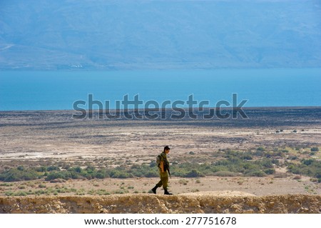 DEAD SEA, ISRAEL - OCT 15, 2014: Israeli  soldier walking alone on a hill in front of the dead sea in Israel close to Qumran