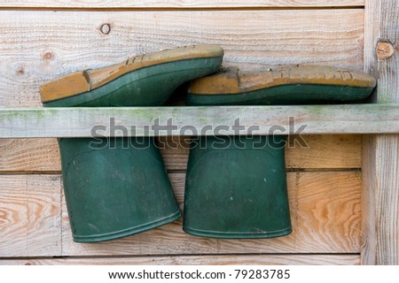 Rubber boots are hanging upside down on the side of a barn on a farm