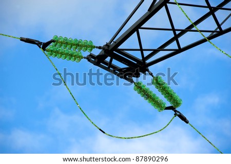 Green energy floating through power cables on an electricity pylon.
