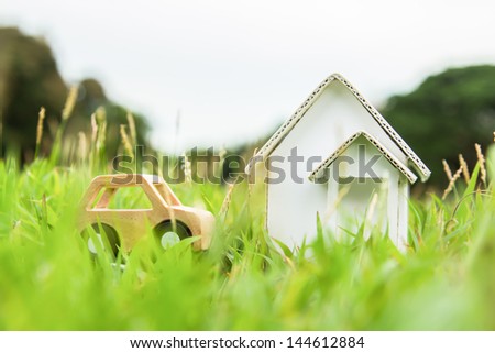 Home and car artificial on the green grass.