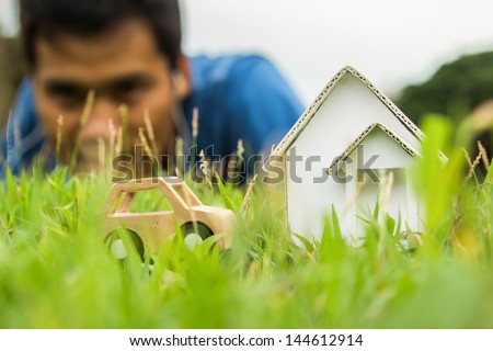 Home and car artificial on the green grass.