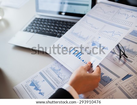 Businessman checking reported profits on the paper and laptop.