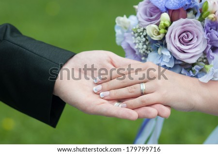 hands of bride and groom with rings and bouquet