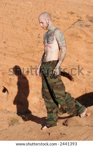 stock photo : Man with tattoos following his shadow