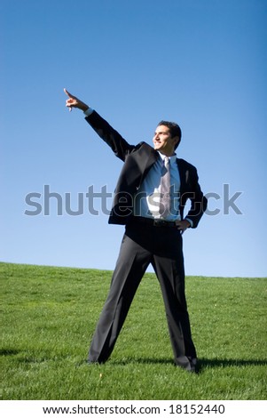 Confident businessman in dark suit pointing to the sky