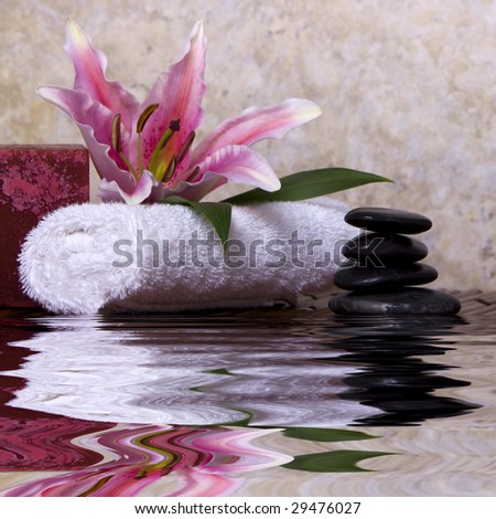 Balanced pebble rocks and pink lily flower on white towel for spa treatment