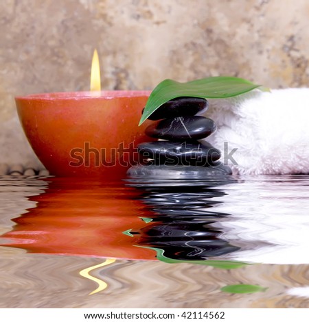 Balanced pebble rocks, candle, white towel set on bamboo for spa treatment