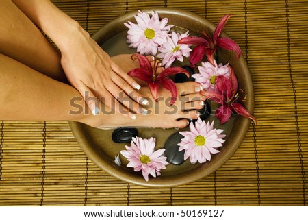 Woman is washing her feet and hands in bowl of water with flowers