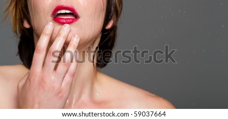 Sexy young woman with short wet hair and red lips running cold water on her face