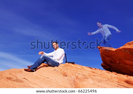 Young man outdoors with his laptop jumping on red rocks