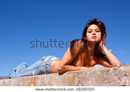 Gorgeous young brunette woman sun tanning on a concrete wall