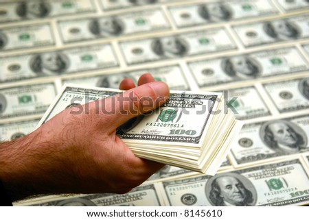 man holding a stack of fresh new crisp hundred dollar bills with sheet of bills in the background