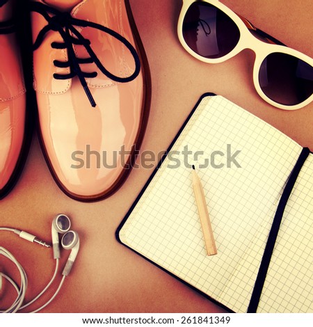 Shiny beige shoes on low heels, white sunglasses, earphones, wooden pencil and small black paper notebook. Retro style, filter Instagram, toning effect, vintage style.