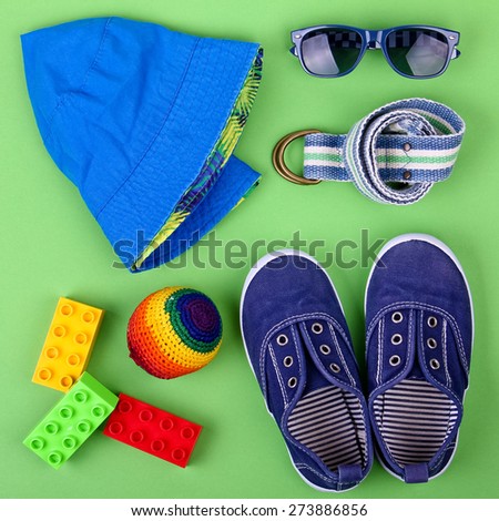 Kid's street outfit and some toys on green background. Overhead view. Teen's concept.