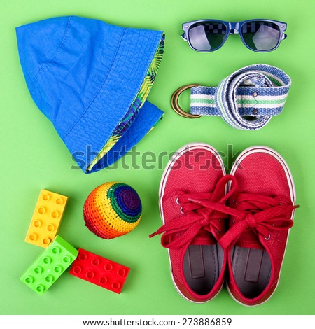 Kid\'s street outfit and some toys on green background. Overhead view.