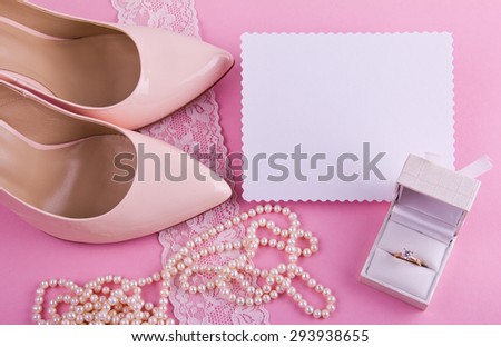 White greeting card with wavy edge. Beige leather shoes with high heel, greeting card and accessories on pink background. Place for your text. Wedding, engagement theme. Good for blogs, instagram.