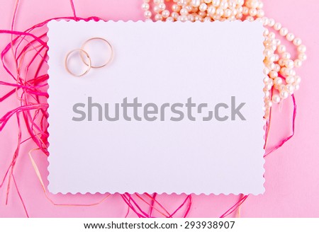 White greeting card with wavy edge is decorated with wedding rings on pink background. Place for your text. Good for blogs, instagram, tweets.