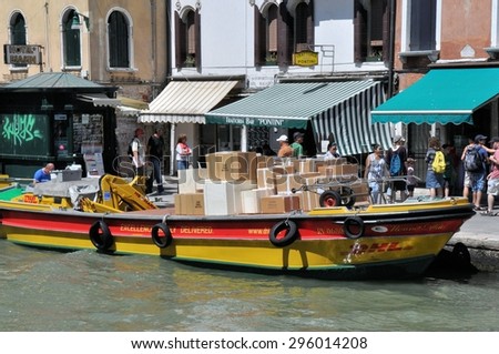 VENICE, ITALY - JULY 18: DHL delivery boat with packages in canal on July 18, 2012 in Venice. Delivery barges are the most common kind of utility vehicle in Venice.