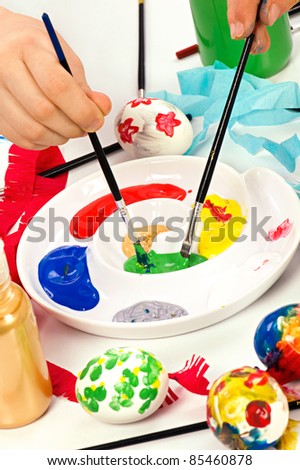 Colorful paints on palette with brushes ready for painting easter eggs. Concept for art and craft classes.