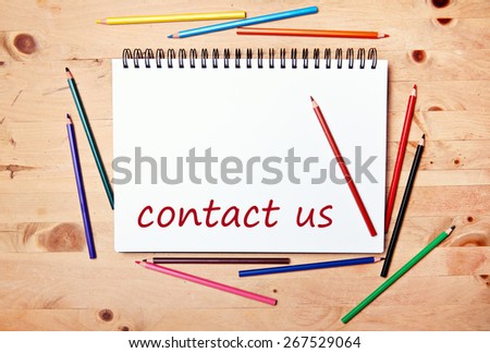 writing pad on wood table with colored pencil - contact us