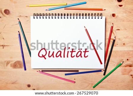 writing pad on wood table with colored pencil - german for quality