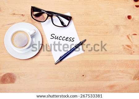 aromatic coffee on wood table with eyeglasses notepad and pen - success