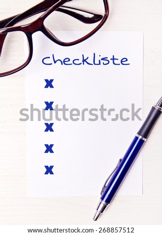 checklist on desktop with office supplies - german for checklist