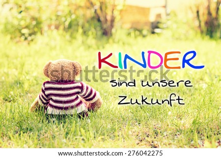 toy - little teddy bear sitting on green grass in garden - german for kids are our future