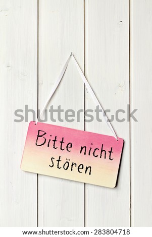 sign on white wood wall - greeting card background german for do not disturb