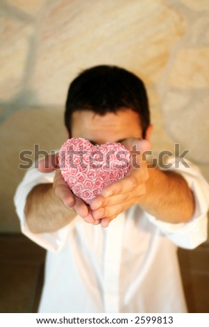 a young man is saying sorry with a heart in his hand