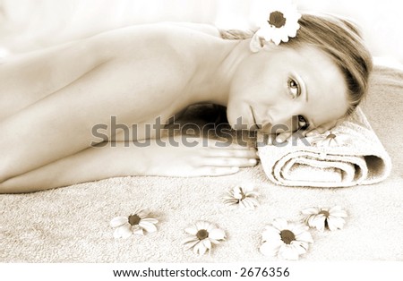 a fresh and beautiful blond woman laying on a towel with flowers