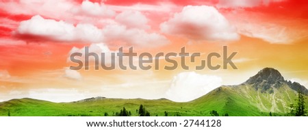 a green meadow on a mountain under the beautiful red and yellow sky in sunset