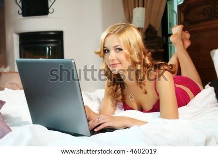 a young beautiful woman is working with her notebook in her bed at home
