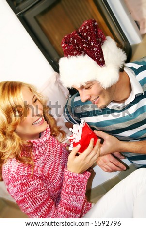 a young attractive couple in christmas time - he is holding a gift