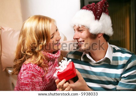 a young attractive couple in christmas time - he is holding a gift