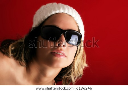 portrait of a beautiful woman with a cap and some sunglasses against red background