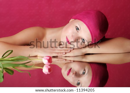 beauty portrait of a young woman in pink with a tulip flower on a mirror