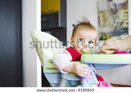 Baby in toddler seat - eating; eyes wide open