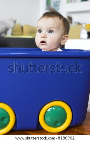 Baby in a plastic tray playing- pretending to drive a car