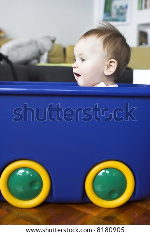 Baby in a plastic tray playing- pretending to drive a car