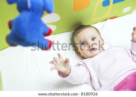 Baby in a crib - reaching for a toy