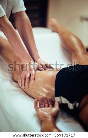 Sports massage. Massage therapist massaging thigh of a male athlete. Toned image