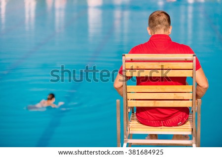 Lifeguard on duty, sitting in lifeguard chair, overlooking pool. Polarizing filter
